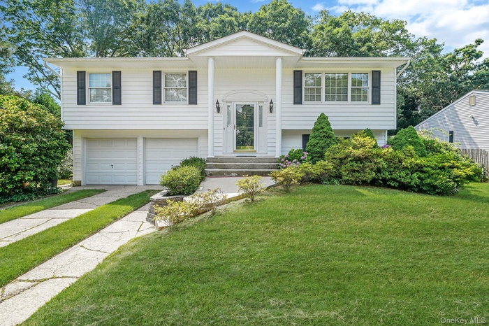 Bi-level home with a garage, a front lawn, and driveway