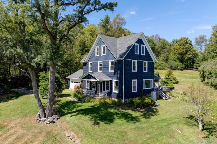 View of front of house featuring roof with shingles, a porch, a front yard, a chimney, and a garage