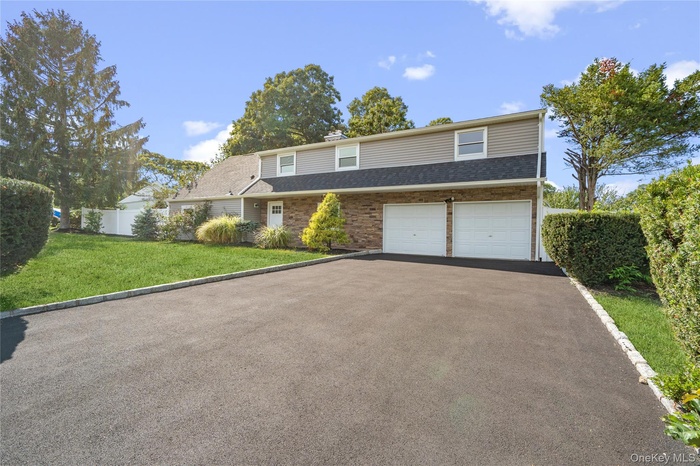 Traditional home with asphalt driveway, a chimney, a garage, and roof with shingles
