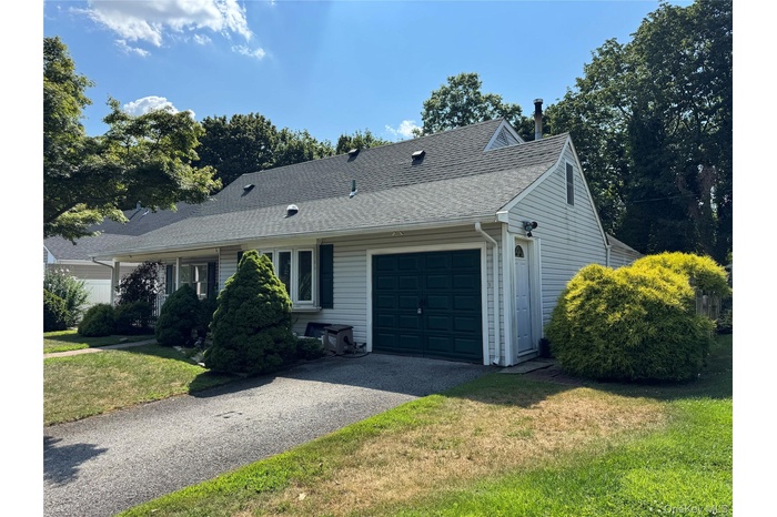 View of front of home featuring a garage, roof with shingles, asphalt driveway, and a front lawn