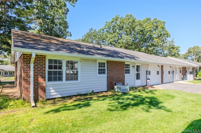 View of front of property featuring asphalt driveway, a front yard, a shingled roof, and an attached garage