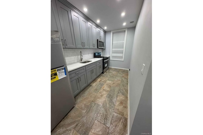 Kitchen featuring stainless steel appliances, a sink, visible vents, gray cabinets, and backsplash