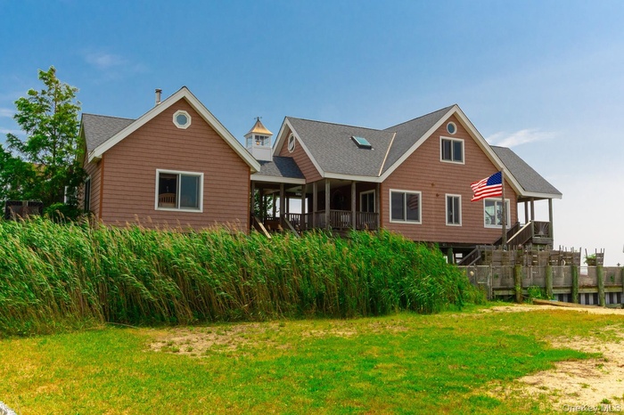 Rear view of house featuring covered porch, a lawn, and roof with shingles