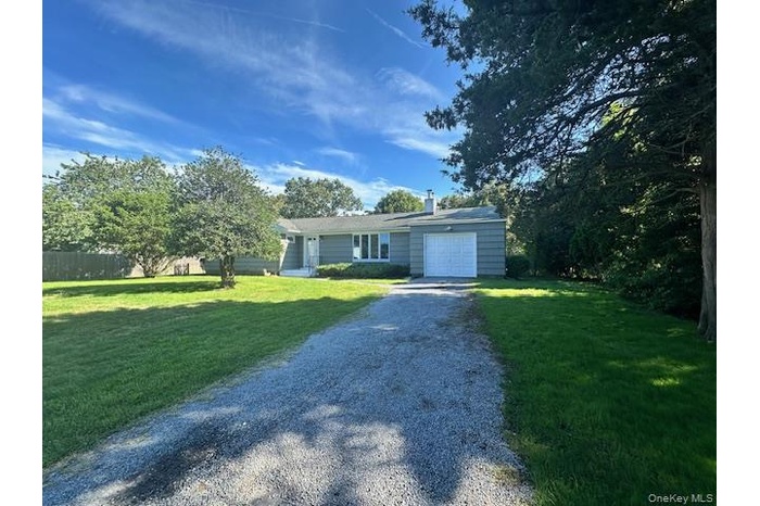 Ranch-style house featuring driveway, an attached garage, and a chimney