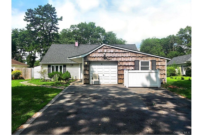 View of front of property with driveway, a chimney, roof with shingles, and a front yard