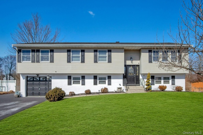 Raised ranch featuring a garage and driveway
