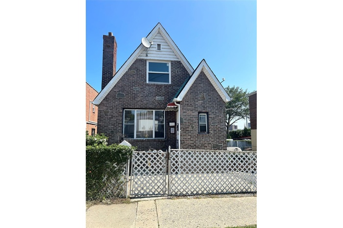 View of front of home with brick siding, a fenced front yard, a gate, and a chimney