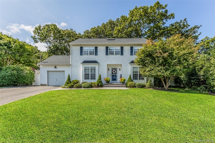 Colonial home with a garage, a front yard, and driveway