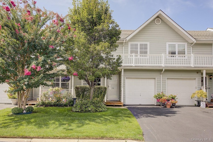 View of front of property featuring asphalt driveway, a front lawn, and a balcony