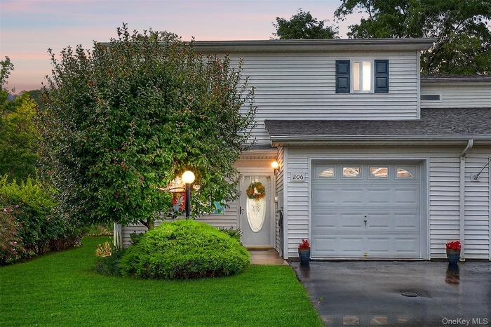 Traditional-style house with a front yard, asphalt driveway, and an attached garage