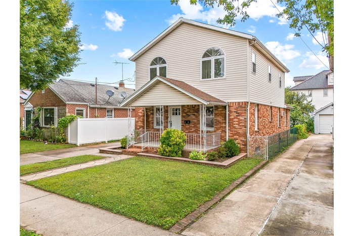 Traditional home with covered porch, brick siding, a detached garage, and an outdoor structure