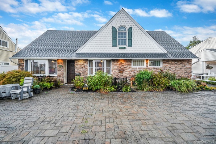 View of front of house with roof with shingles and stone siding