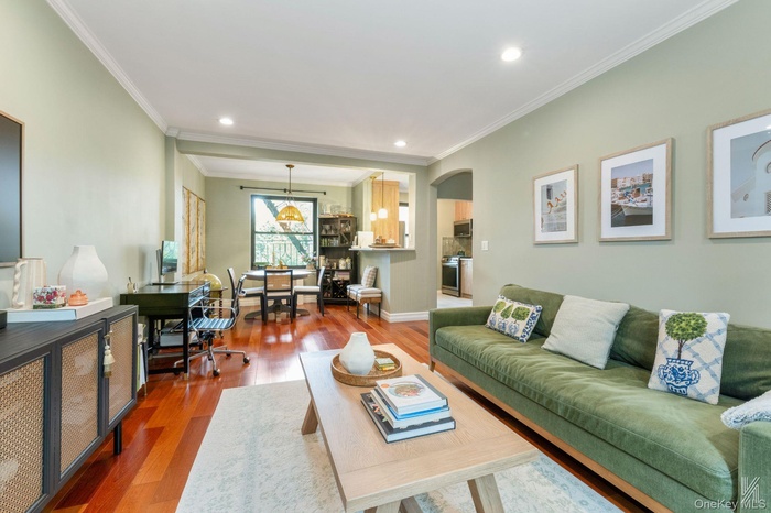 Living area featuring ornamental molding, wood finished floors, arched walkways, and recessed lighting