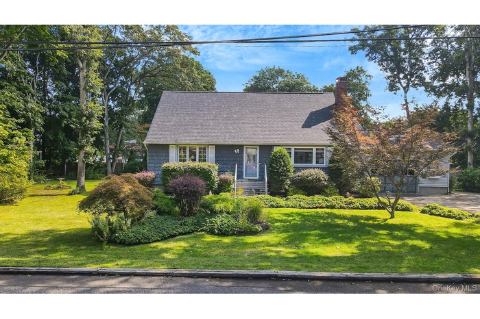 New england style home with a front lawn, a chimney, a shingled roof, and a garage