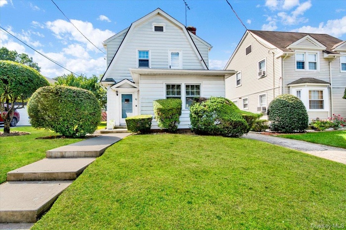 Dutch colonial with a gambrel roof, a chimney, and a front lawn