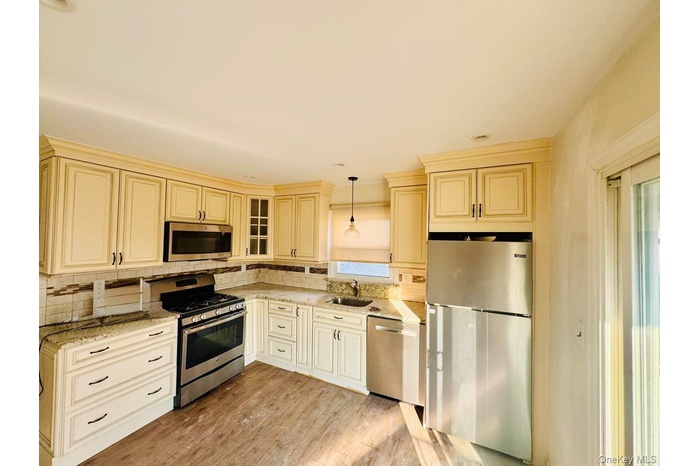 Kitchen featuring cream cabinets, stainless steel appliances, hanging light fixtures, and recessed lighting