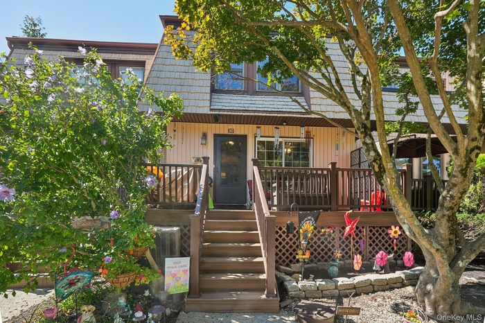 Front of house featuring mansard roof, a deck, and stairway