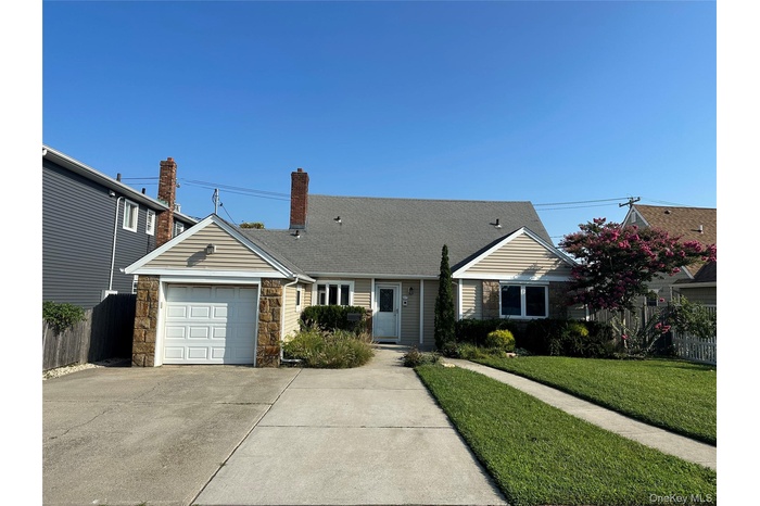 View of front of property with concrete driveway, stone siding, a garage, a chimney, and a shingled roof