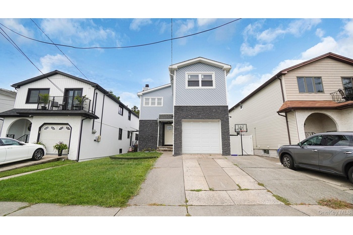 View of front of home with driveway, brick siding, a front yard, and a garage