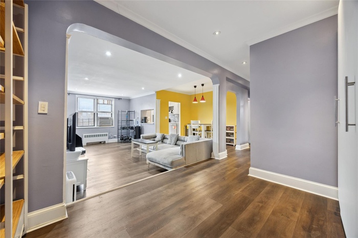 Living area featuring ornamental molding, baseboards, radiator heating unit, and wood finished floors