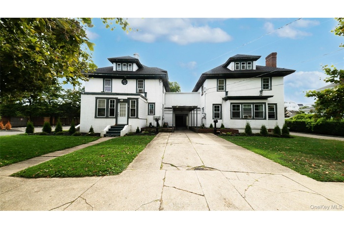 Traditional style home with a chimney, concrete driveway, a front yard, and stucco siding
