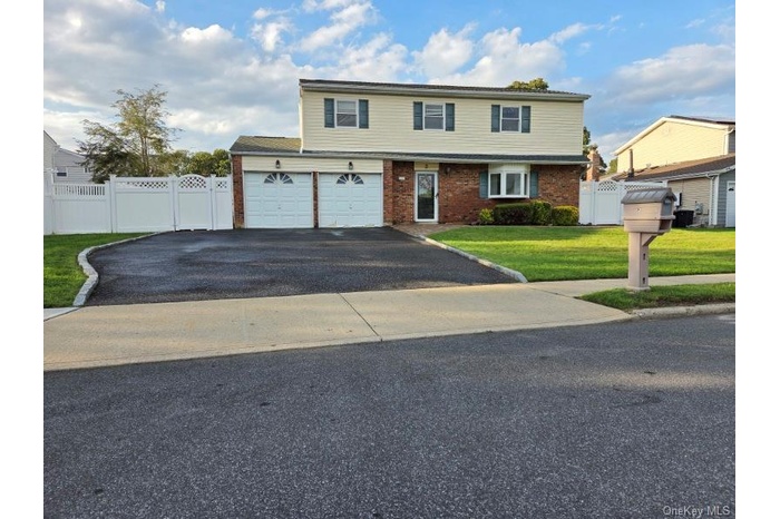 View of front of house featuring driveway, brick siding, a gate, and an attached garage