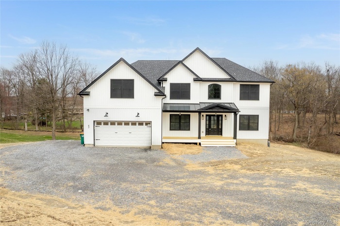 Modern farmhouse style home with a standing seam roof, driveway, a shingled roof, and a garage