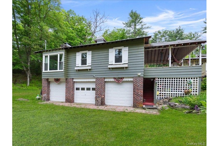 View of front of home with brick siding, an attached garage, driveway, and a front lawn