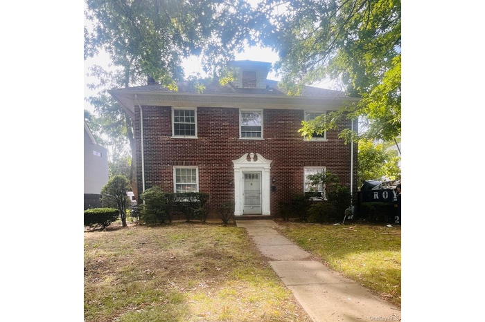 Colonial-style house with brick siding and a front yard