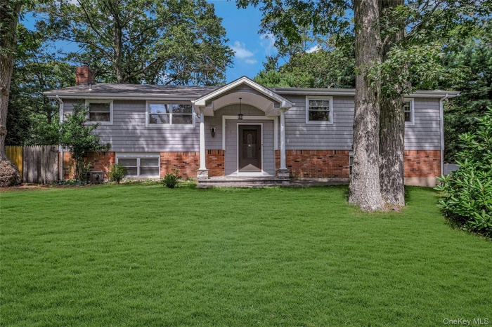 Bi-level home featuring a chimney and brick siding