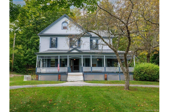 View of front of home featuring a porch, a front lawn, and view of wooded area