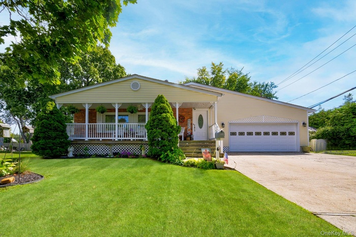 View of front facade featuring a porch, a front lawn, and concrete driveway