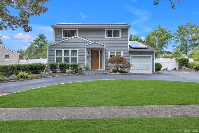 Traditional-style home featuring roof mounted solar panels, a garage, and asphalt driveway