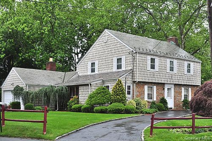 View of front of home featuring a front lawn & a circular driveway