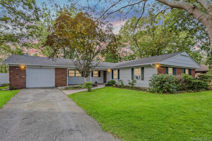 Single story home with brick siding, an attached garage, asphalt driveway, a yard, and a shingled roof