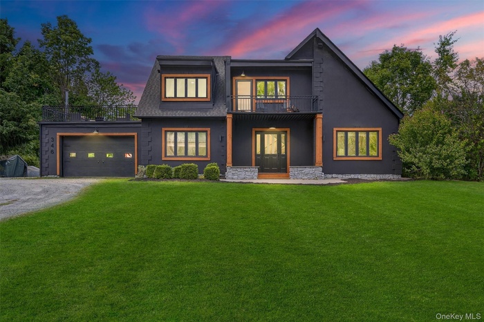 View of front of home with driveway, a front lawn, stucco siding, a balcony, and french doors