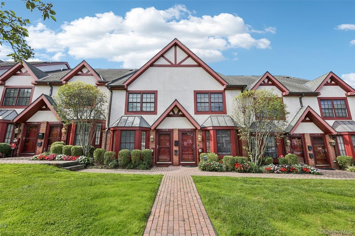 Tudor-style house featuring stucco siding, a front yard, and brick siding