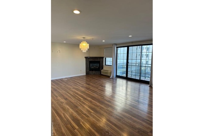 Unfurnished living room featuring a glass covered fireplace, recessed lighting, dark wood-type flooring, and a chandelier