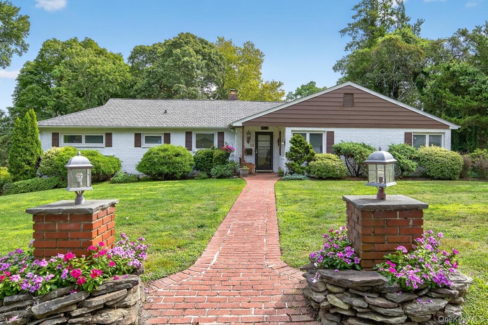 Single story home featuring a chimney, a front lawn, and brick siding