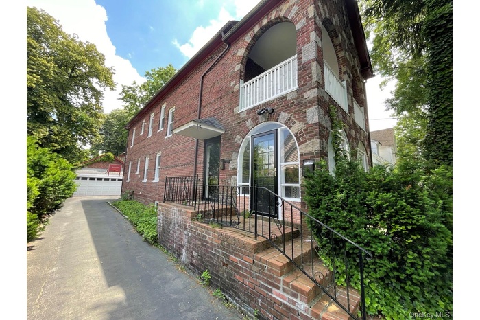 View of home's exterior with brick siding, an outdoor structure, a balcony, and a detached garage