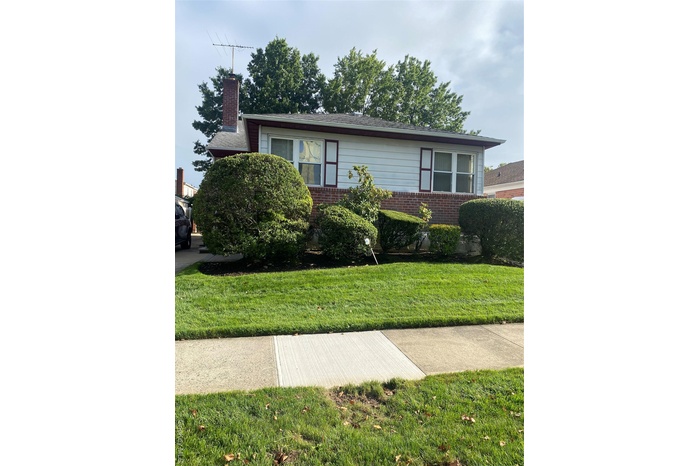 View of front of house with brick siding, a chimney, and a front yard