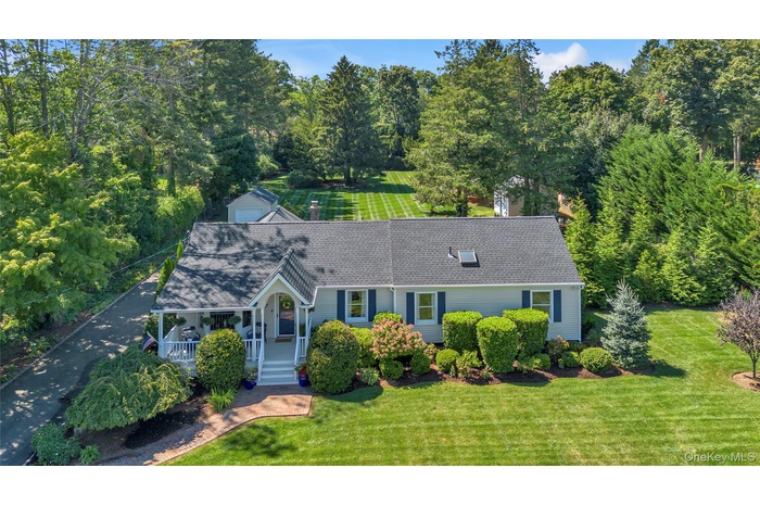 View of front facade with a front yard, a shingled roof, and covered porch