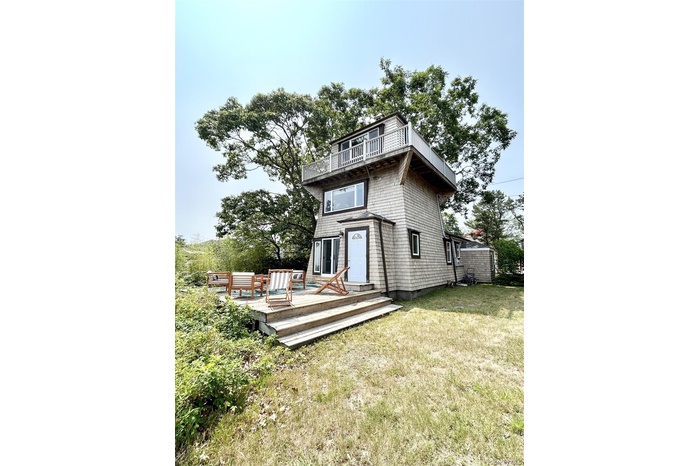 Back of property with a yard, a wooden deck, and a balcony