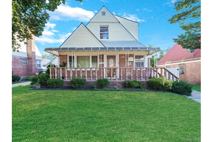 Bungalow-style home with covered porch, a front lawn, and brick siding