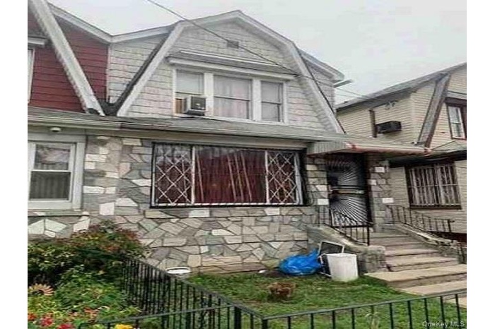 View of home's exterior with a gambrel roof and stone siding
