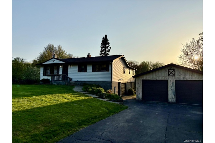 Ranch-style house with a garage, a front yard, a chimney, and an outbuilding