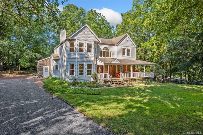 Victorian-style house with covered porch, a chimney, and view of wooded area