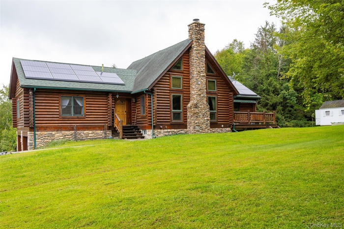 Back of house with solar panels, a yard, roof with shingles, and an outdoor structure