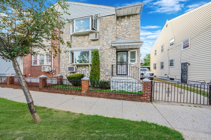 View of front facade featuring a fenced front yard, stone siding, and a gate