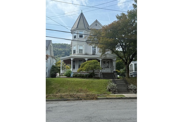 Victorian-style house with covered porch, a front lawn, and stairway